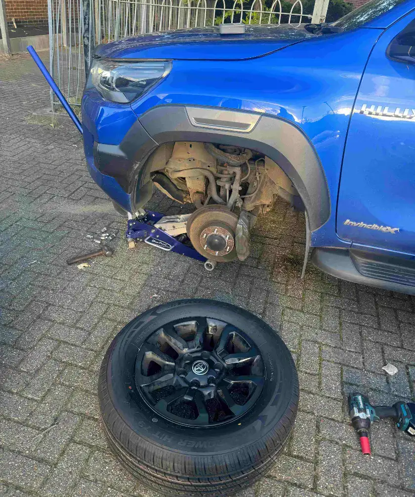 Locking wheel nut removal in King’s Lynn on a blue Toyota Hilux, wheel off the hub on a driveway with the jack under the car